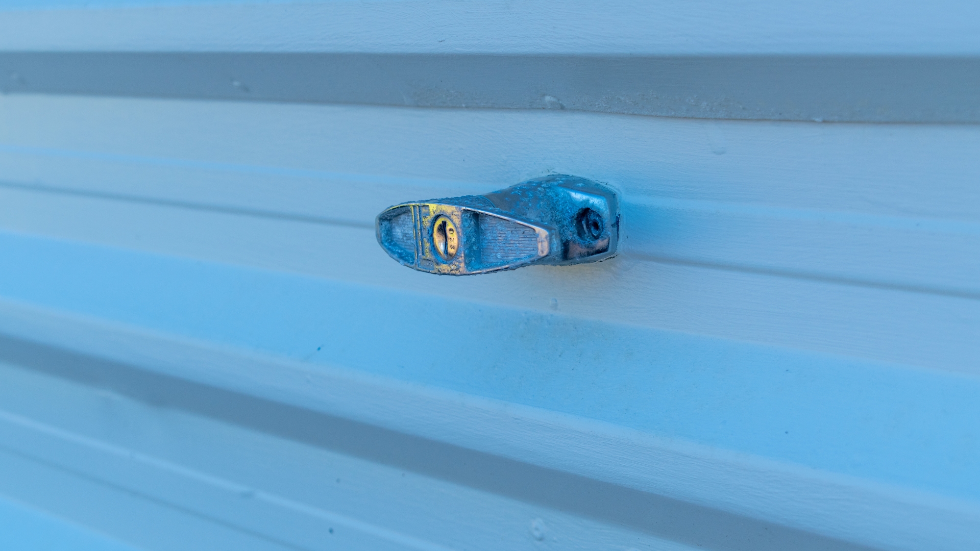 A metal T-handle garage door lock