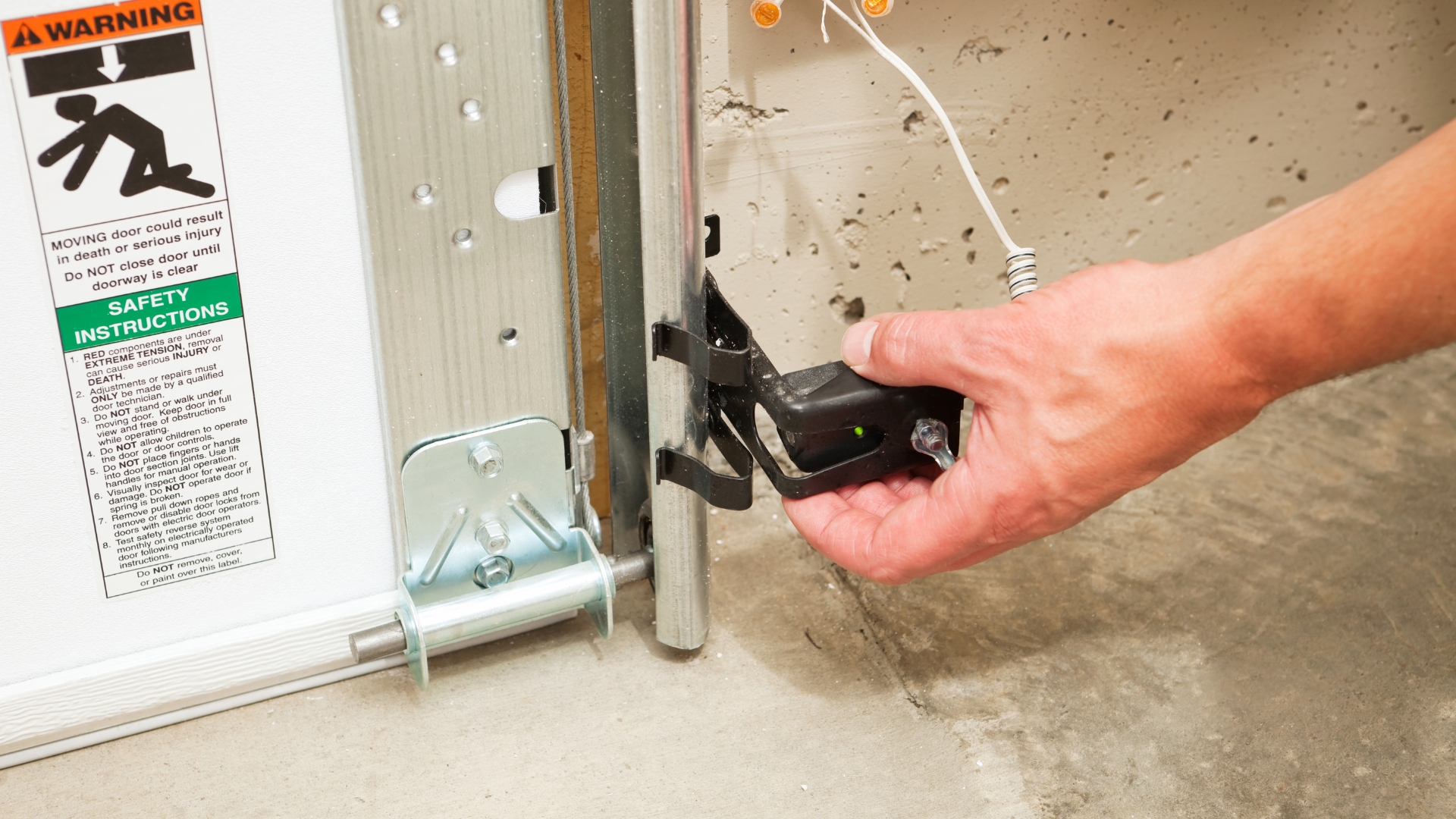 A garage door expert adjusting the safety sensor