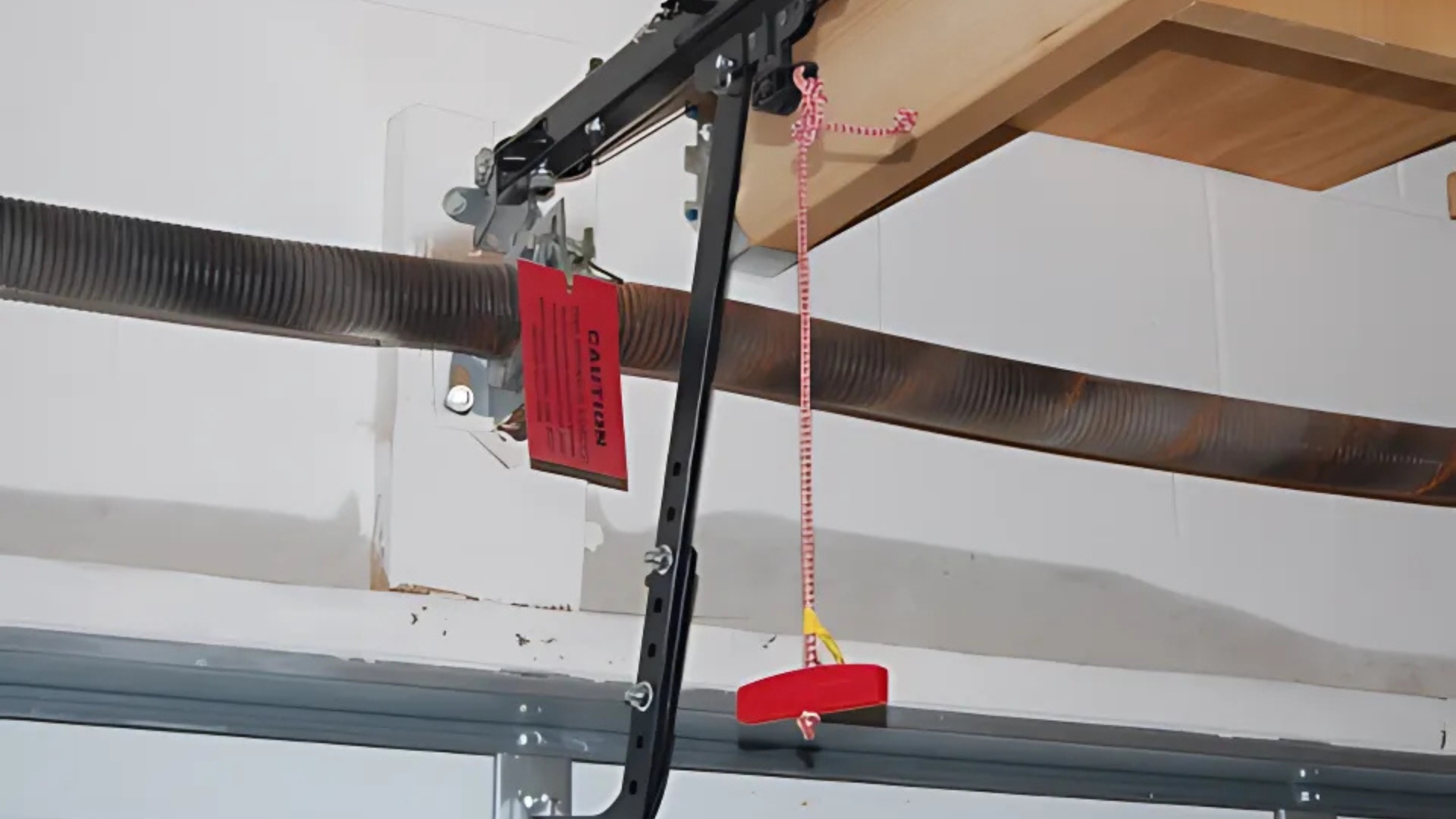 Garage safety release cord with red handle for manual operation.