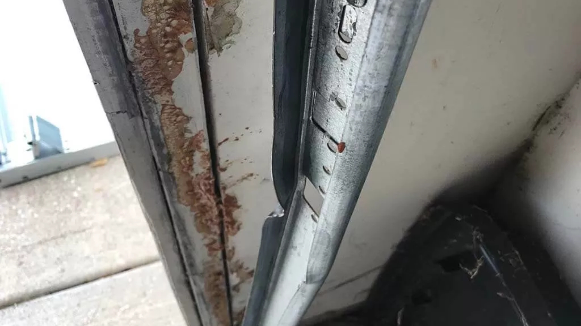 Close-up of a stuck garage door due to a bent and rusted metal track.